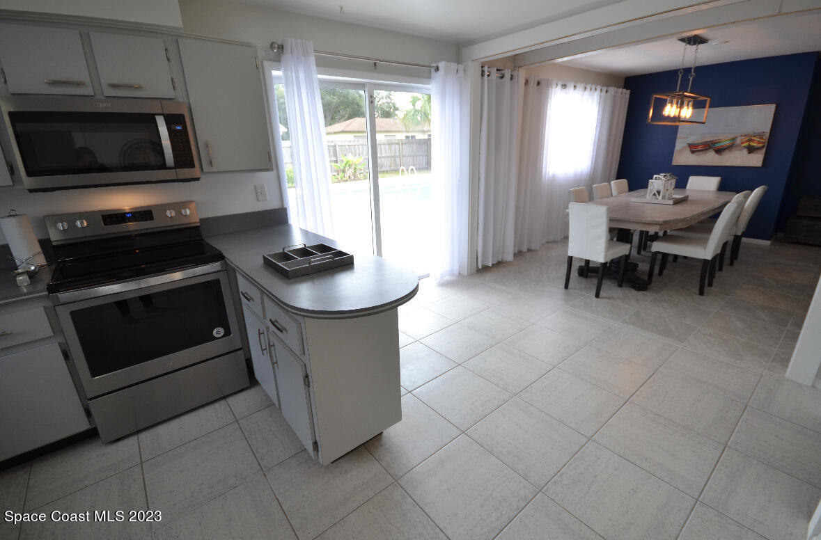 2785 Locksley Road Melbourne, FL 32935 - Photo 23 of 34 a kitchen with granite countertop a stove a sink and a microwave