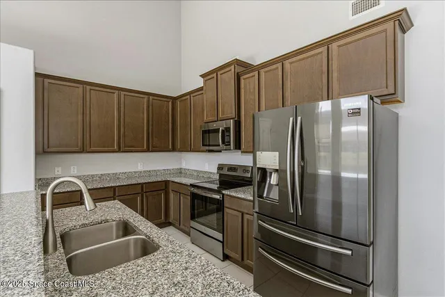a kitchen with kitchen island granite countertop a refrigerator oven a sink and dishwasher