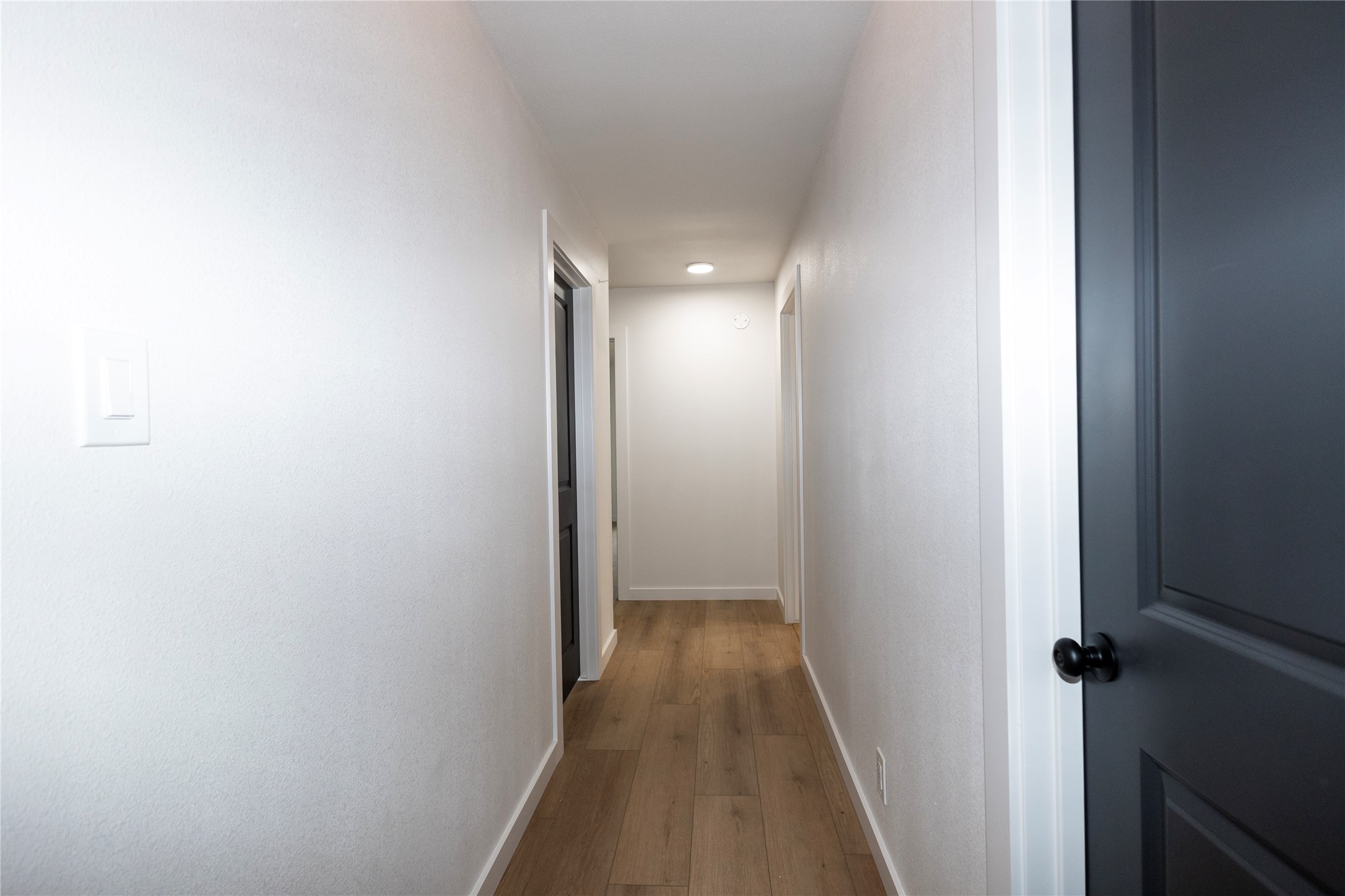205 Bello Circle Georgetown, TX 78628 - Photo 20 of 36 A well-lit hallway with natural wood-tone flooring and clean white walls, featuring modern doors.