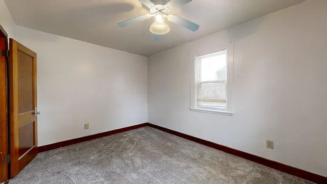 an empty room with a window and a fan