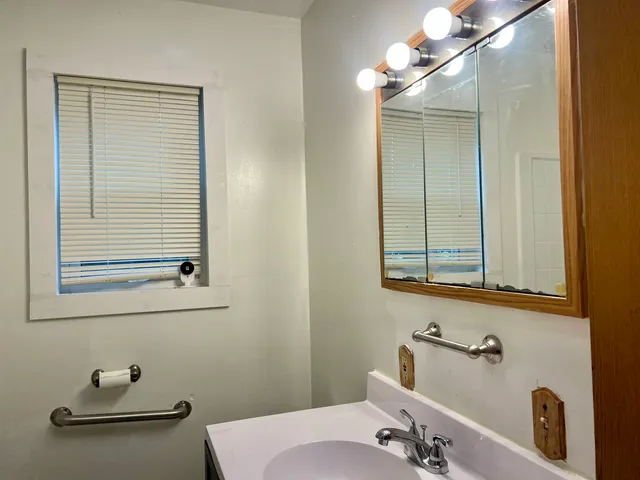 a bathroom with a sink and mirror with window