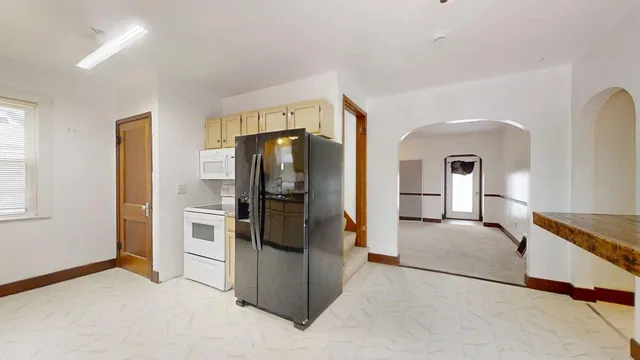 a living room with stainless steel appliances kitchen island granite countertop furniture and a refrigerator