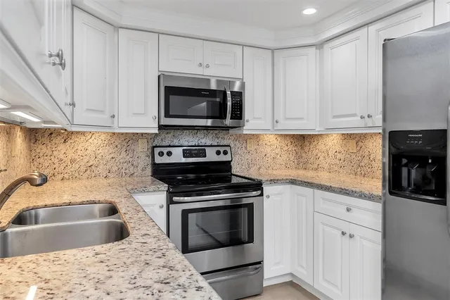 a kitchen with white cabinets sink and stainless steel appliances