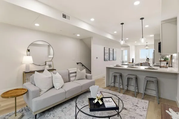 a living room with furniture a rug kitchen and a chandelier