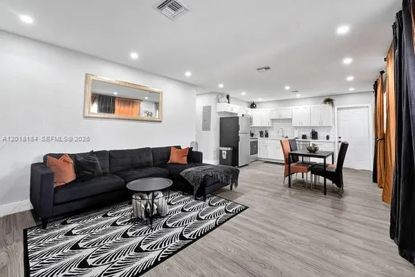 a living room with furniture and a dining table with wooden floor