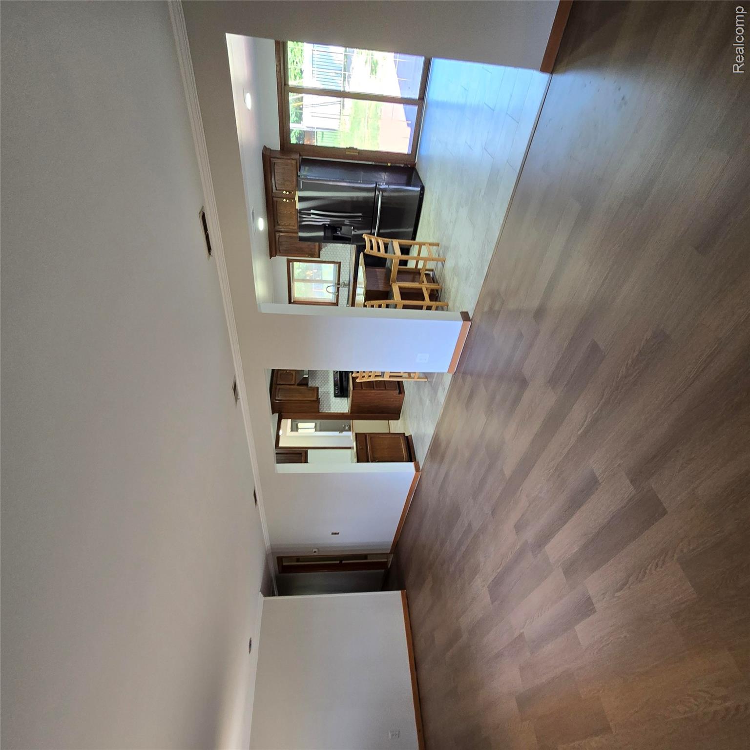 311 Nevada Avenue Rochester, MI 48309 - Photo 15 of 70 Open-concept living area with wood-finish flooring extending into the kitchen featuring dark wood cabinetry, stainless steel appliances, and a central island with bar seating