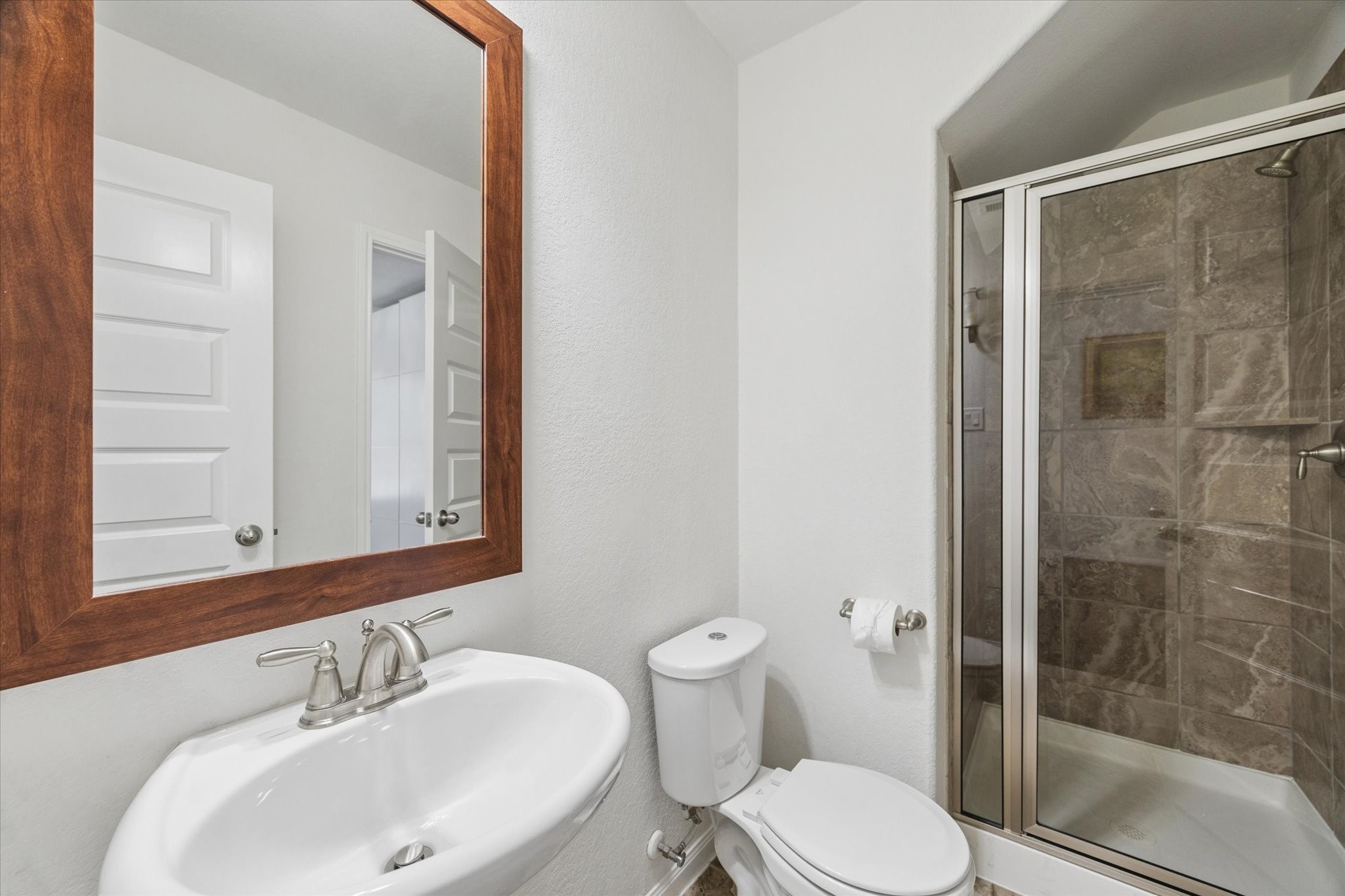7015 Riata Hills Lane Spring, TX 77379 - Photo 5 of 33 A secondary bathroom located next to the flex room offers a practical and efficient layout with a pedestal sink topped by a classic wood-framed mirror. The shower and tub combination features a neutral shower curtain and tiled surround, making it easy to maintain. Light finishes keep the bathroom feeling clean and functional—ideal for everyday use or guests.