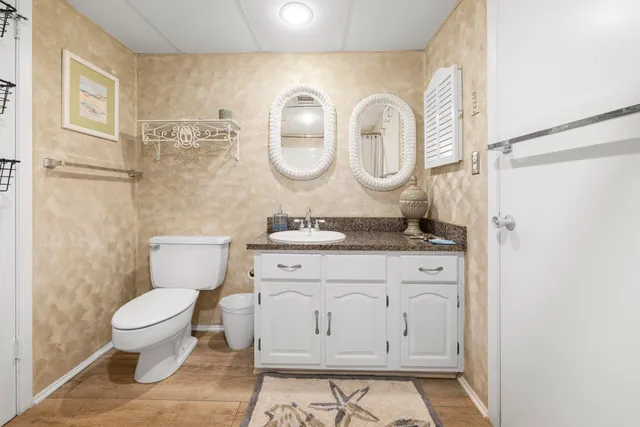 a bathroom with a granite countertop toilet a sink and a mirror