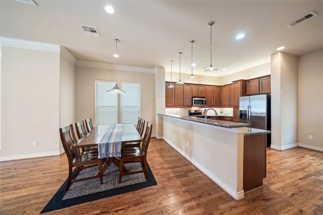 a kitchen with stainless steel appliances granite countertop a sink a stove and a wooden floor