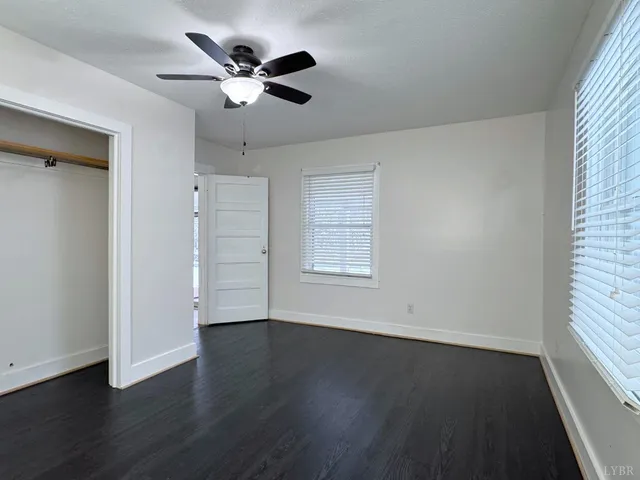 an empty room with wooden floor and ceiling fan
