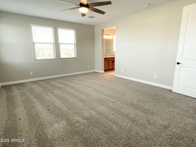 an empty room with windows and ceiling fan