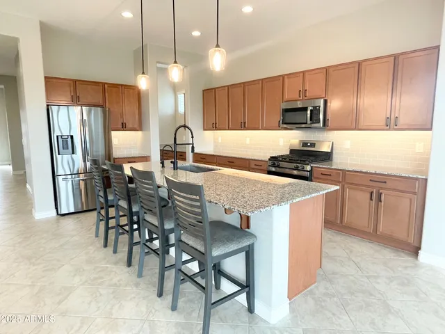 a kitchen with kitchen island granite countertop a table chairs microwave and refrigerator