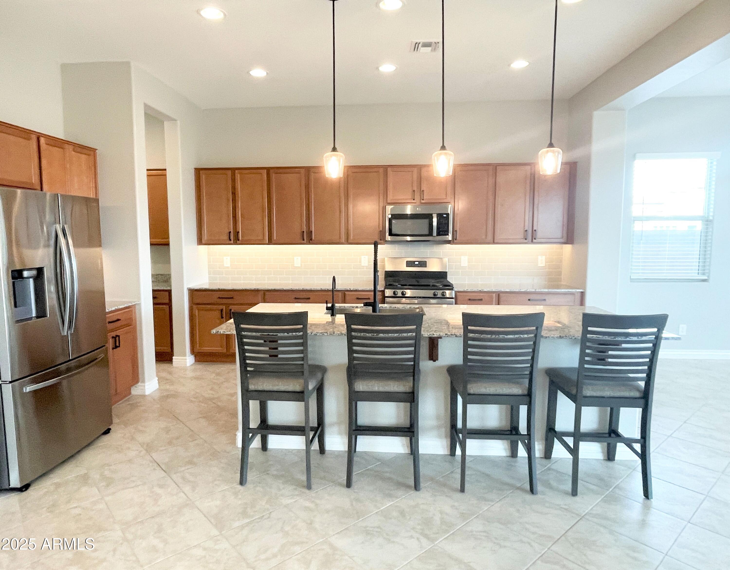 21046 East Mayberry Road Queen Creek, AZ 85142 - Photo 7 of 32 a kitchen with a table chairs refrigerator and microwave
