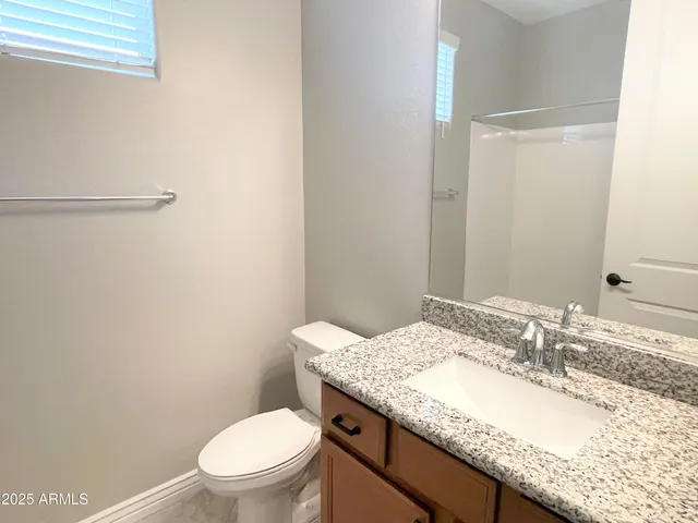 a bathroom with a granite countertop sink a toilet and a mirror