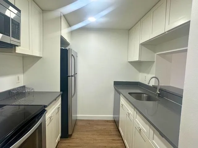 a kitchen with stainless steel appliances granite countertop a sink and a refrigerator