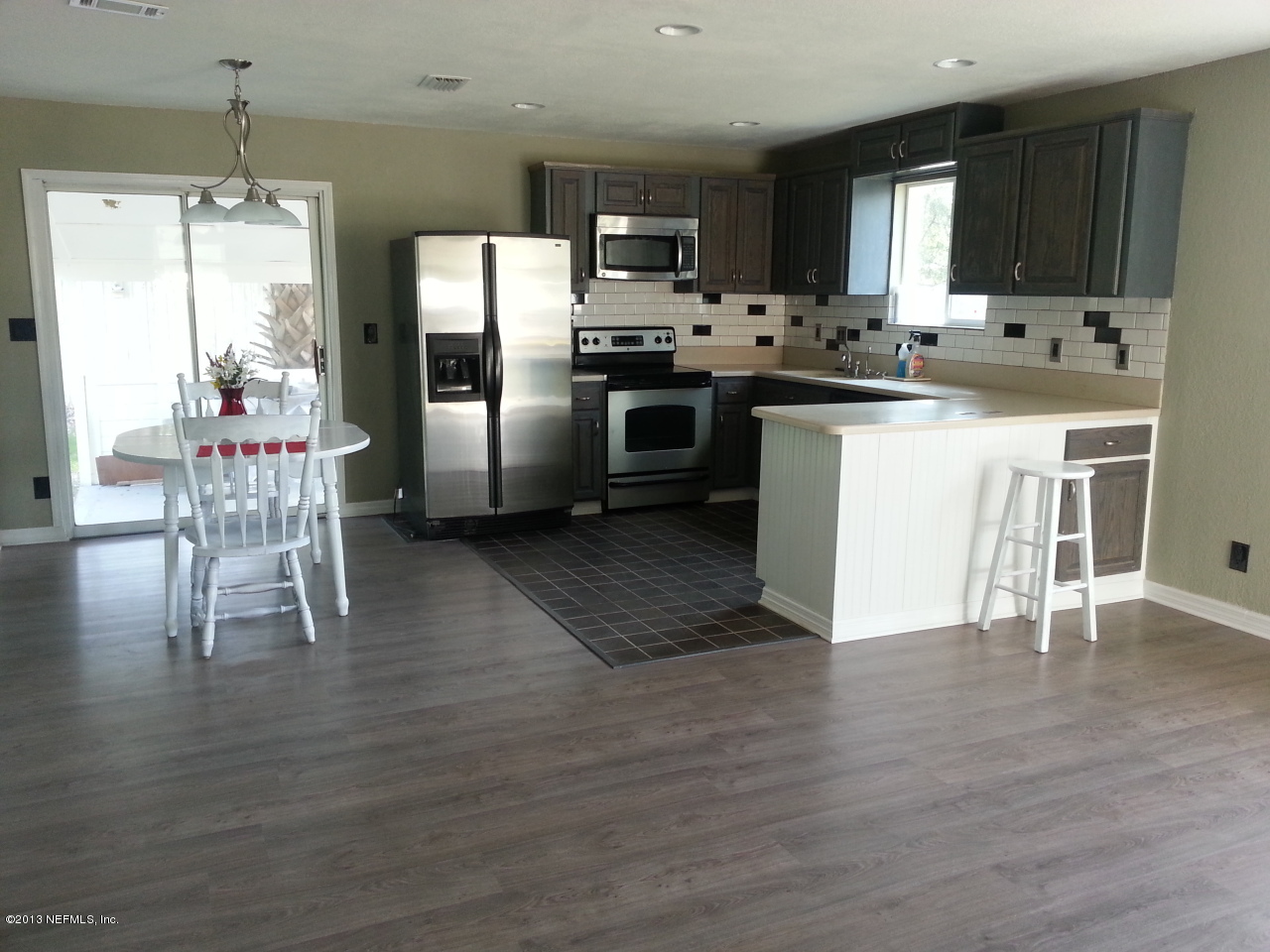 7253 Sandhurst Road South Jacksonville, FL 32277 - Photo 1 of 13 a kitchen with stainless steel appliances granite countertop a refrigerator a stove a sink dishwasher a dining table and chairs with wooden floor