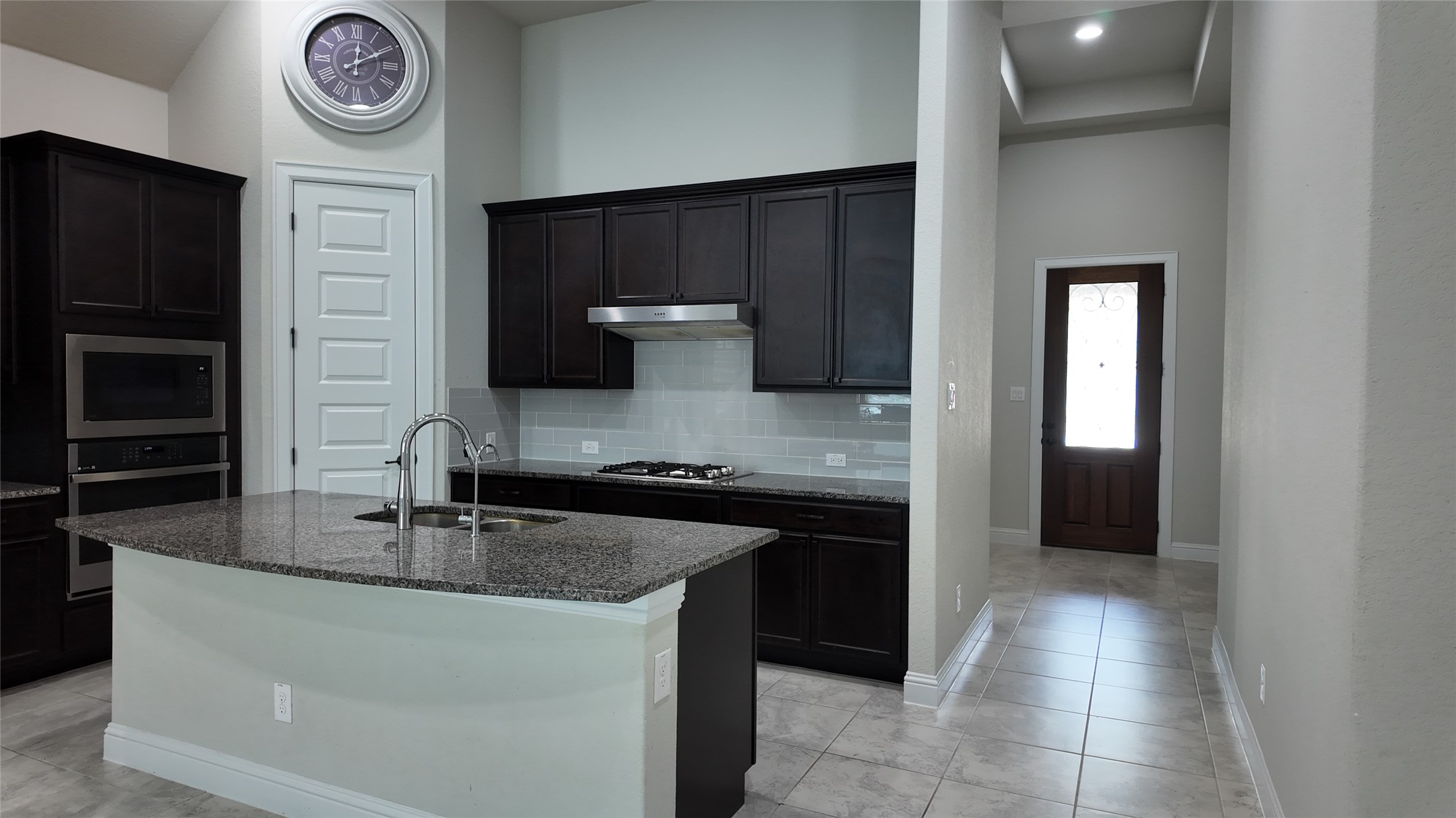 2320 Base Burner Path Leander, TX 78641 - Photo 9 of 24 A well-appointed kitchen features dark wood cabinetry, granite countertops, and modern appliances, creating a stylish culinary space.