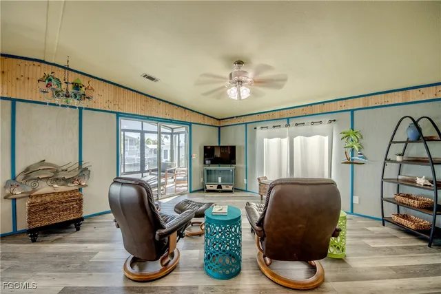 a living room with furniture a flat screen tv and a floor to ceiling window