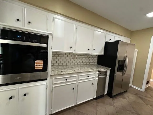 a kitchen with granite countertop white cabinets and stainless steel appliances