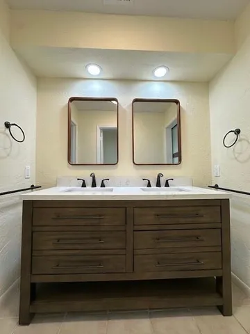 a bathroom with double vanity sink and two mirror