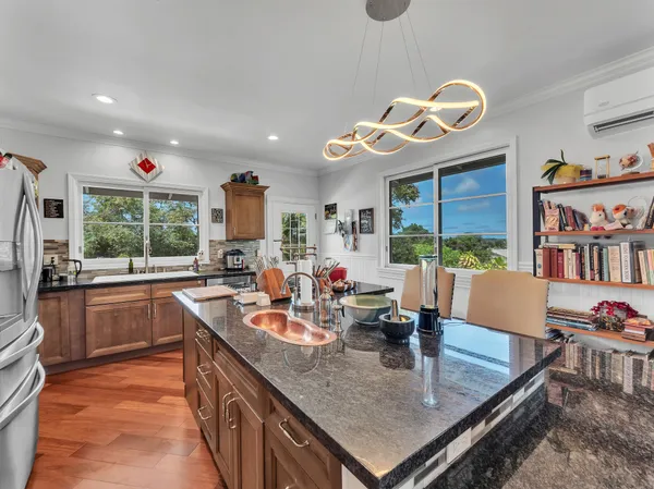 a kitchen with stainless steel appliances granite countertop a sink dishwasher and a flat tv screen next to a large window