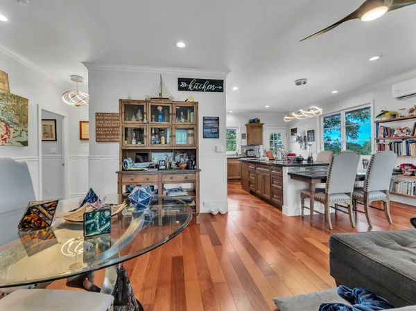 a living room with stainless steel appliances kitchen island granite countertop furniture and a wooden floor