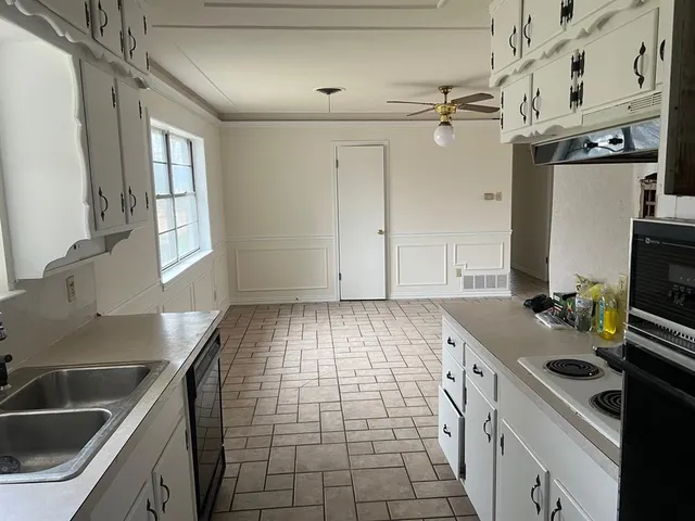 a kitchen with a sink a stove cabinets and a window
