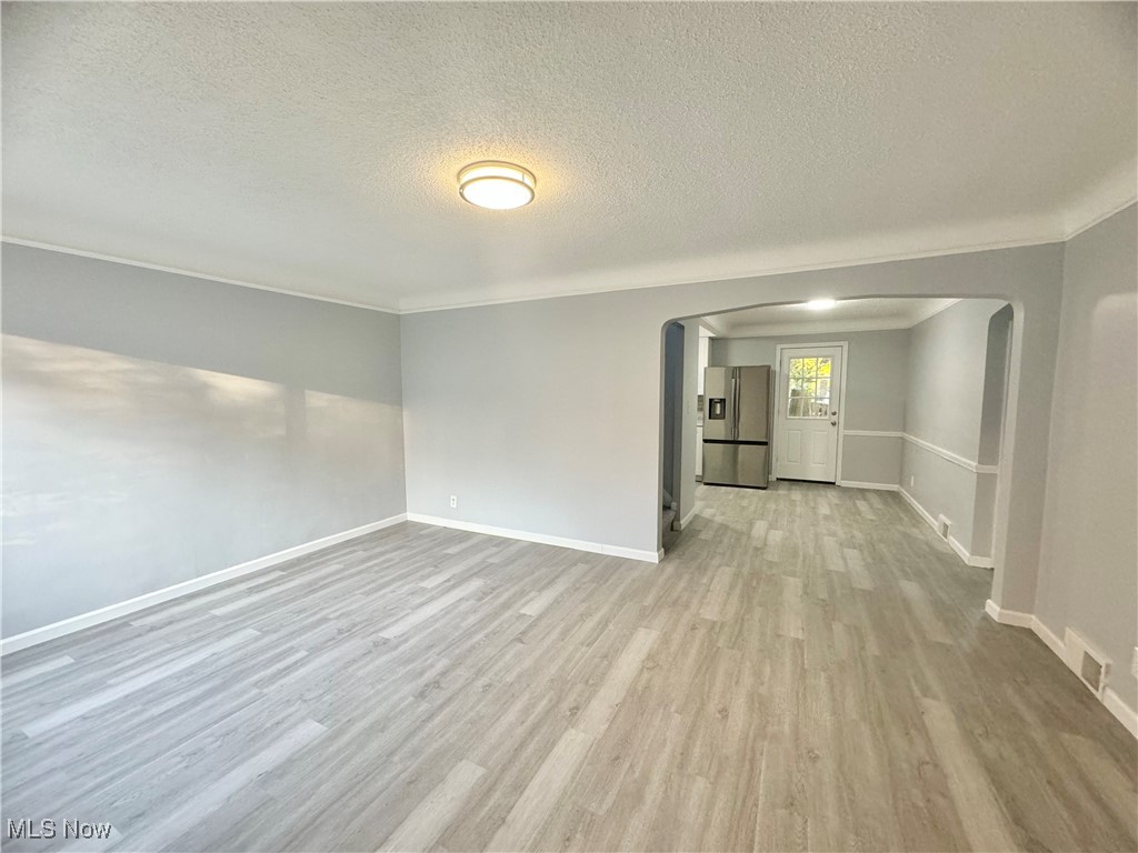 1215 Avondale Road Cleveland, OH 44121 - Photo 8 of 27 Empty room with a textured ceiling, ornamental molding, and light wood-type flooring