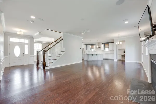 a view of a hallway with wooden floor and a kitchen