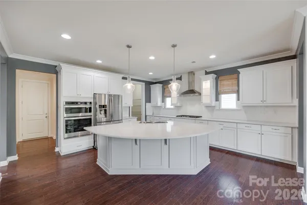 a large white kitchen with wooden floors and stainless steel appliances