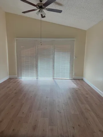 an empty room with wooden floor and fan