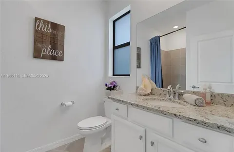 a bathroom with a granite countertop toilet sink and mirror