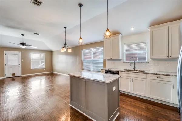 a kitchen with stainless steel appliances granite countertop a sink a stove a refrigerator and white cabinets with wooden floor