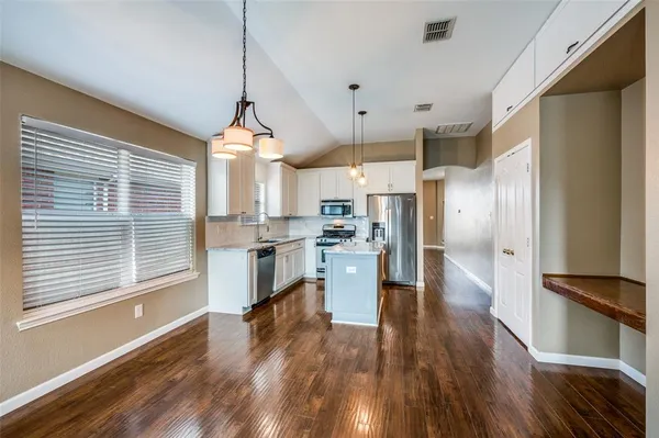 a kitchen with a refrigerator a stove and a wooden floor