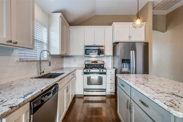 a kitchen with granite countertop a sink stove and refrigerator