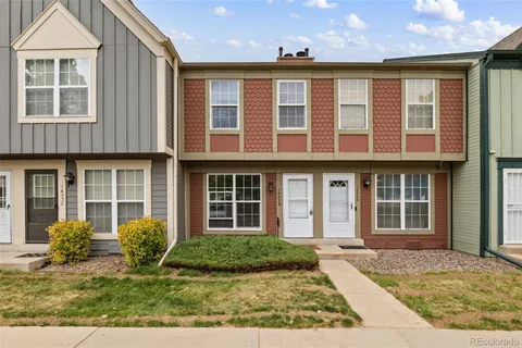 front view of a brick house with a lots of windows and plants