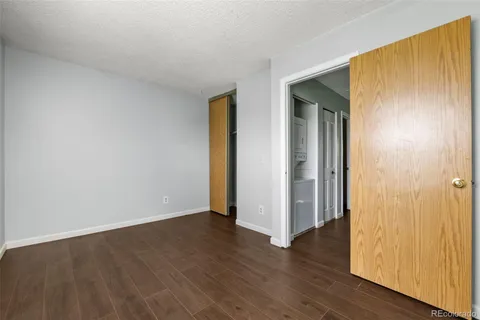 a view of an empty room with wooden floor and closet
