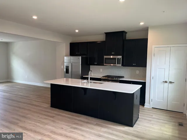 a kitchen with stainless steel appliances a sink dishwasher a refrigerator and a stove with wooden floor