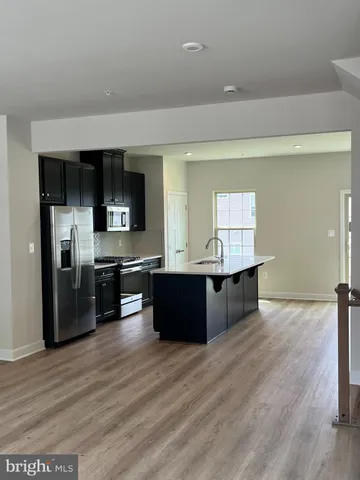 a large kitchen with a large counter top stainless steel appliances and wooden floor