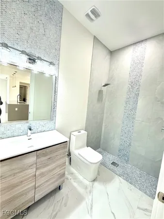 a bathroom with a granite countertop sink toilet a mirror and shower