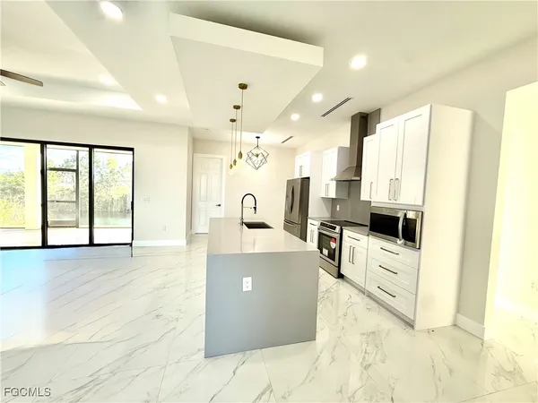 a large kitchen with stainless steel appliances a large counter top a stove and a refrigerator