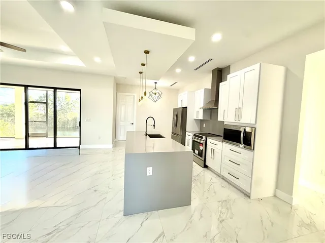 a large kitchen with stainless steel appliances a large counter top a stove and a refrigerator