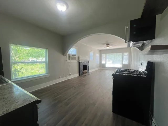 an empty room with wooden floor cabinet and windows