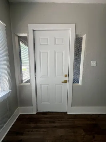 an empty room with wooden floor closet and windows