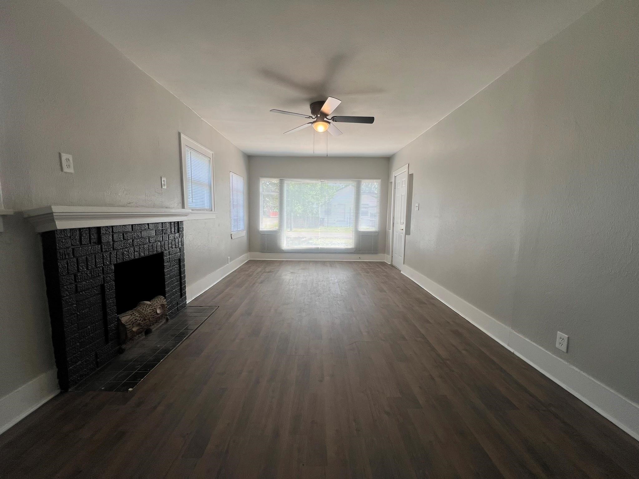 2531 Stevens Street Houston, TX 77026 - Photo 8 of 39 an empty room with wooden floor fireplace and windows