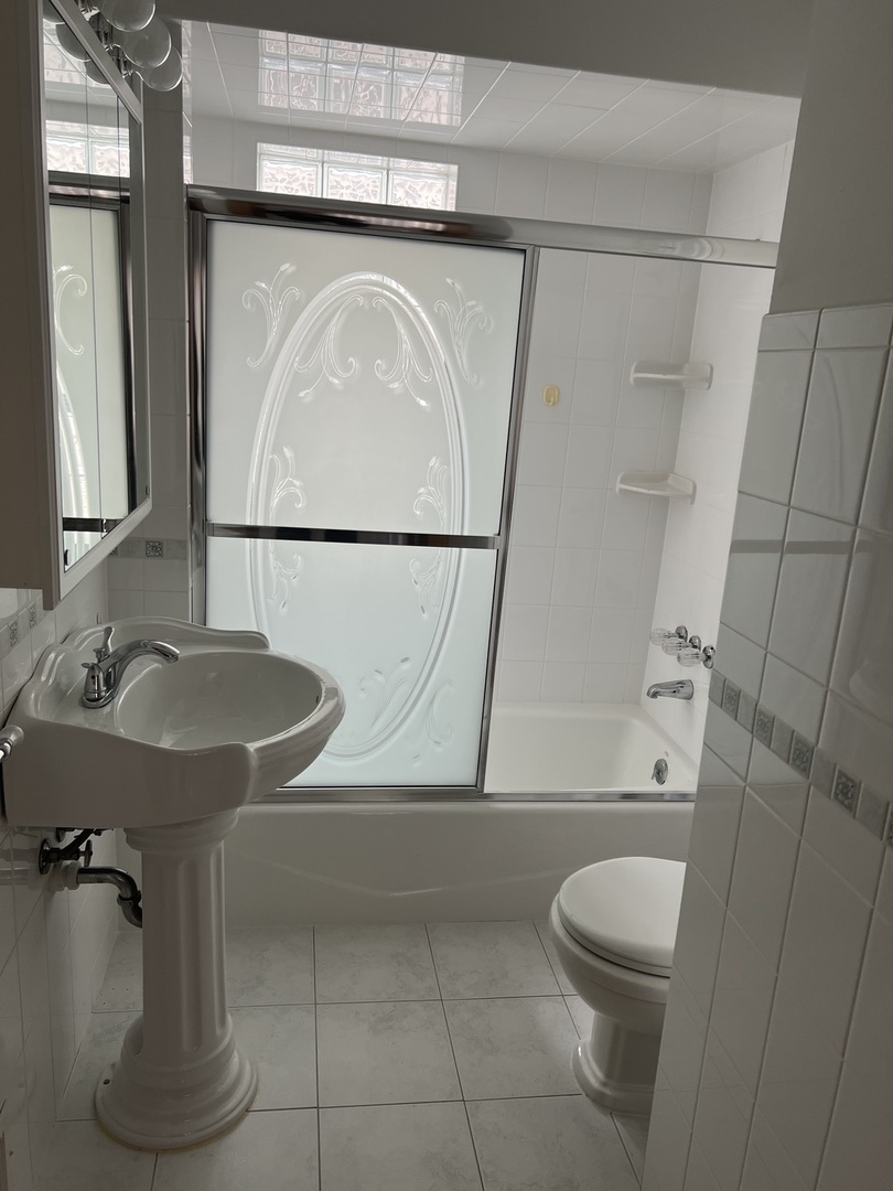 7416 West Addison Street Chicago, IL 60634 - Photo 9 of 19 a bathroom with a sink a toilet and a mirror