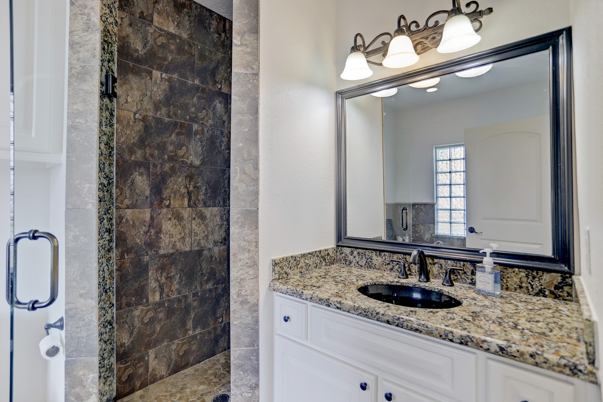 14362 Calvary Road Willis, TX 77318 - Photo 18 of 44 a bathroom with a granite countertop sink a mirror and shower