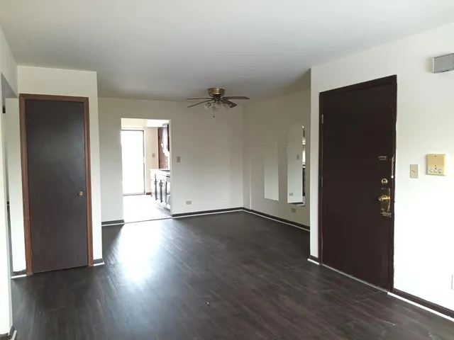 an empty room with wooden floor and a ceiling fan
