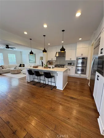 a kitchen with stainless steel appliances granite countertop a stove top oven a sink dishwasher a dining table and chairs with wooden floor