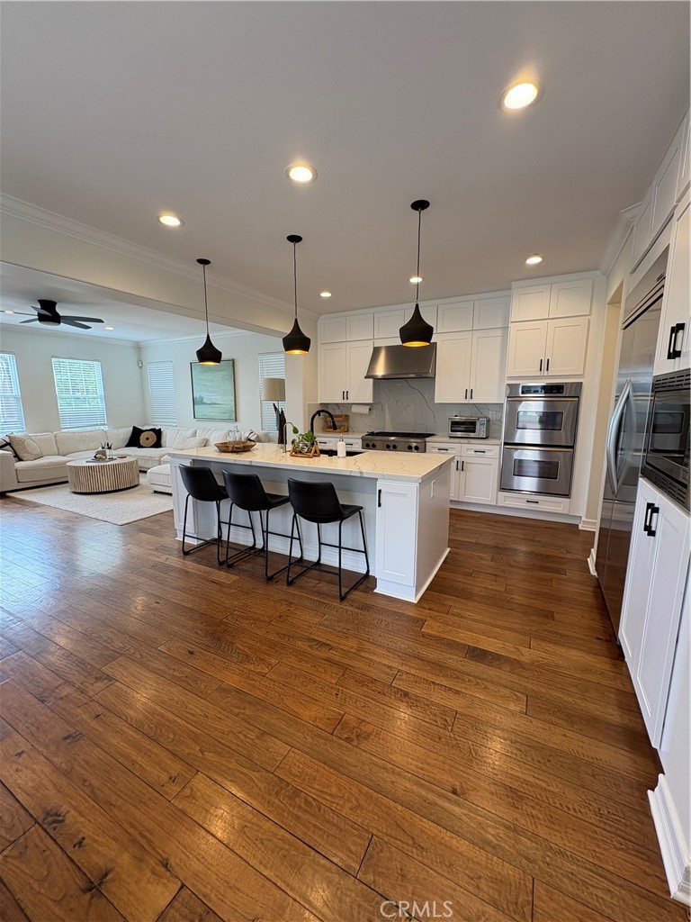 72 Downing Street Ladera Ranch, CA 92694 - Photo 6 of 24 a kitchen with stainless steel appliances granite countertop a stove top oven a sink dishwasher a dining table and chairs with wooden floor
